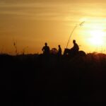 Homens em cavalos no pôr do sol